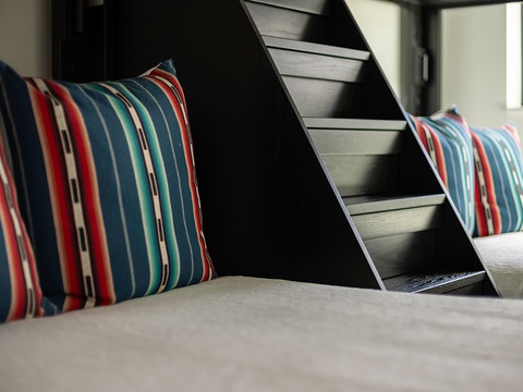 Rest easy in this cozy bedroom featuring bunks and cheerful striped accents—perfect for friends or family traveling together.