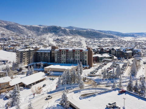Aerial view of a winter resort nestled in snow-covered mountain terrain, offering access to skiing and outdoor recreation in a scenic alpine town.