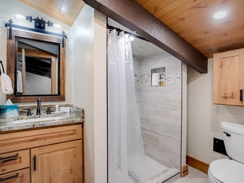 Step into your private retreat with a walk-in shower, granite vanity, and warm wood accents that blend rustic charm with modern comfort.