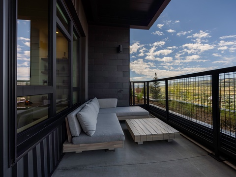 Unwind on your private covered balcony with sleek outdoor seating, where you'll soak in sweeping views of the surrounding landscape under open skies.