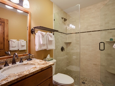 Freshen up in your private bathroom featuring a spacious walk-in shower with modern tile, plush towels, and a granite vanity—everything you need to feel at home.