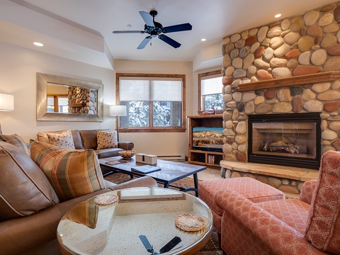 Sink into plush seating by your crackling stone fireplace as natural light pours through the windows. This cozy living space invites you to unwind after a day of adventure, with warm textures and a mountain retreat atmosphere.