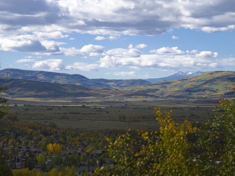 Expansive mountain valley framed by autumn foliage and snow-capped peaks, showcasing the property's scenic location in a tranquil rural setting.