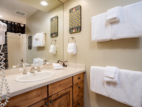 Your private bathroom features a roomy vanity with warm wood cabinetry, thoughtful décor, and plush towels ready for a soothing soak after a day of adventure.