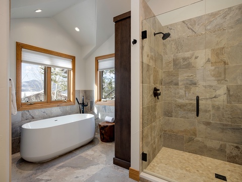Indulge in your private spa-like retreat with a soaking tub, walk-in shower, and serene mountain views framed by warm wood accents.