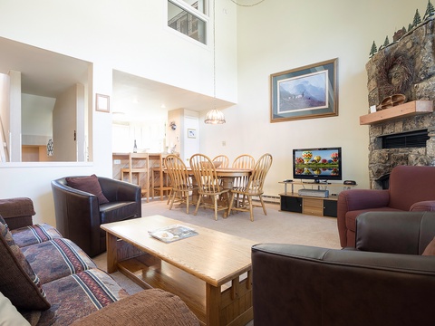 Gather with loved ones in your spacious living area, where soaring ceilings and a stunning stone fireplace create a warm, inviting atmosphere for memorable conversations and cozy evenings together.