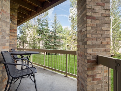 This covered balcony frames views of lush trees and green space, offering your peaceful retreat for morning coffee or evening relaxation just steps from your door.