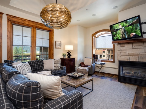 Sink into plush seating by the fireplace, enjoy your favorite shows, and gaze out at mountain views—your cozy retreat awaits with warm wood accents and modern comfort.