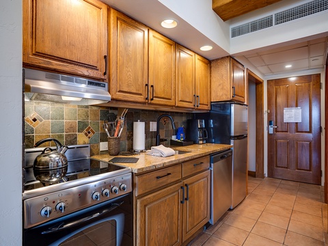 Your fully equipped kitchen features warm wood cabinetry, granite counters, and stainless steel appliances—perfect for preparing home-cooked meals during your mountain getaway.