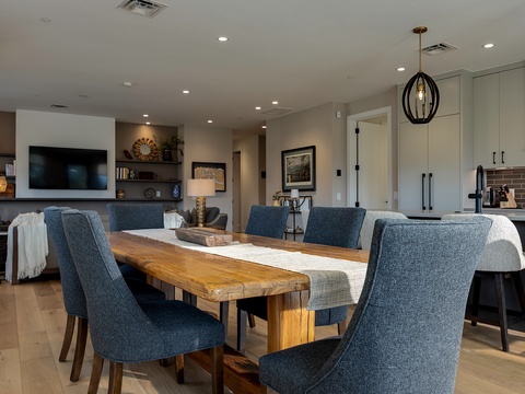 Gather around the warm wood dining table where your group can share meals and stories in this stylish open-concept space, perfectly connecting kitchen and living areas.