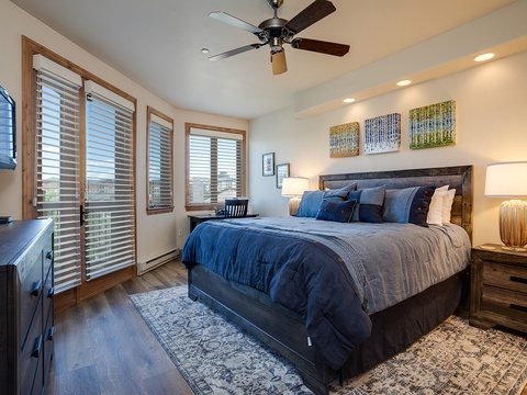 Sink into plush bedding and wake refreshed beneath the gentle hum of a ceiling fan. Large windows frame scenic views, while warm lighting sets a peaceful mood after your mountain adventures.