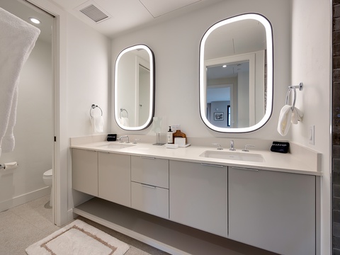 Step into your modern dual-vanity bathroom with sleek backlit mirrors and pristine countertops, where you'll enjoy spa-like mornings preparing for your day.