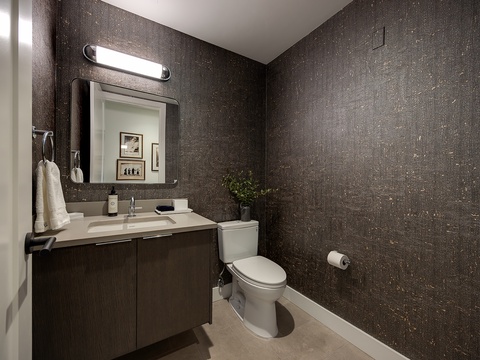 Step into your sleek, modern powder room with its textured walls and warm lighting. Fresh towels await you, and thoughtful touches like fresh greenery make this space feel refined and welcoming.