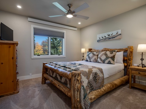 Your cozy retreat features a handcrafted log bed with plush bedding, warm wood furnishings, and a ceiling fan for year-round comfort. Natural light and rustic charm create the perfect mountain escape.