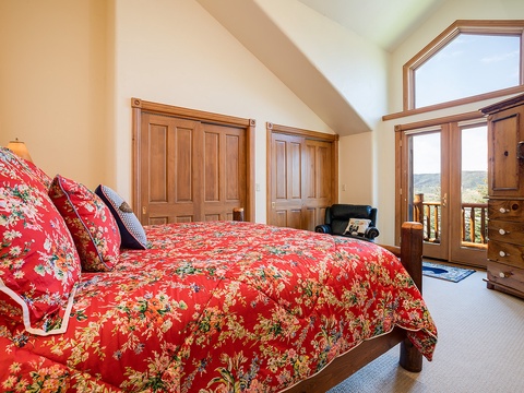 Sink into this cozy bed and wake up to sweeping mountain views through your private balcony doors, with elegant wood furnishings creating a warm retreat.