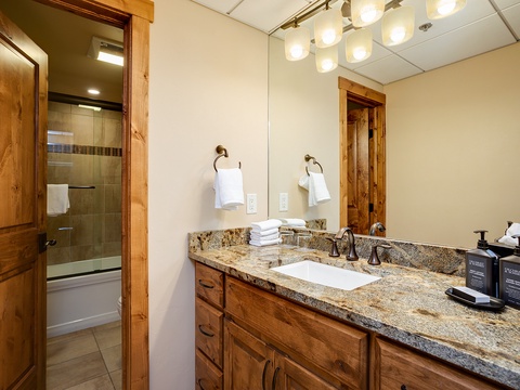 Step into your private bathroom with warm wood accents, gleaming granite counters, and a spacious tub-shower combo—perfect for refreshing after a day of adventure.