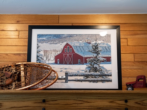 A cozy shelf displaying vintage snowshoes, rustic charm, and a peaceful winter barn scene—thoughtful touches that make your stay feel warm and inviting.