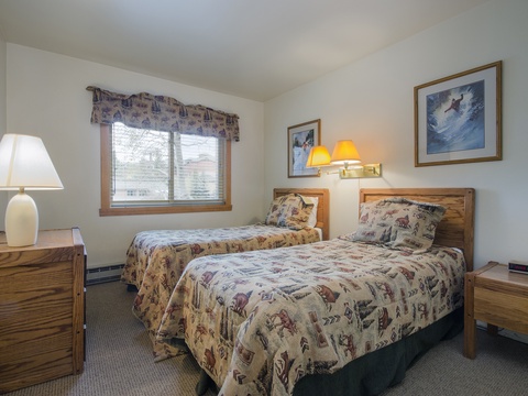 Your cozy mountain retreat features two comfortable twin beds dressed in rustic-inspired linens, warm bedside lighting, and charming ski-themed artwork. Wake up refreshed and ready for adventure.