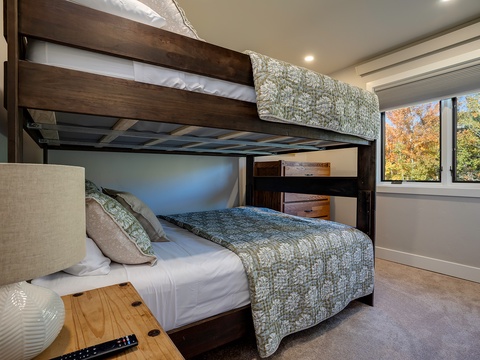 Rest easy in this smart bunk room where clever design maximizes space without sacrificing comfort. Wake to autumn views through modern windows that fill your mornings with natural light and seasonal beauty.