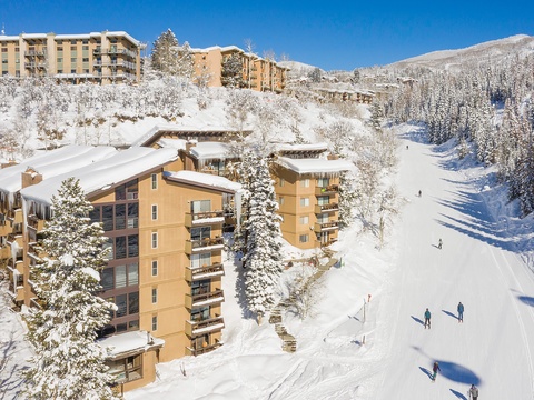 Ski-in location nestled on the mountainside, surrounded by snow-covered evergreens and pristine winter slopes, with easy access to nearby lifts and trails.