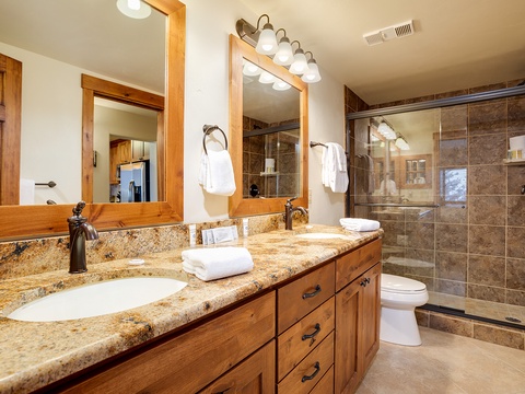 Step into your spa-like bathroom with elegant granite counters, warm wood cabinetry, fluffy towels, and a spacious walk-in shower that invites you to unwind after a day of adventure.