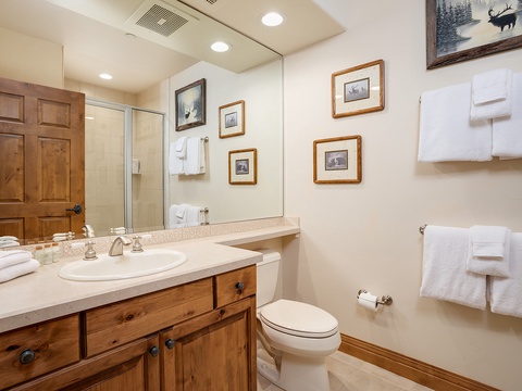 Step into your private bathroom, where rustic wood cabinetry and charming wildlife art create a cozy retreat. Fresh towels await, and the bright mirror reflects the warmth of this thoughtfully appointed space.