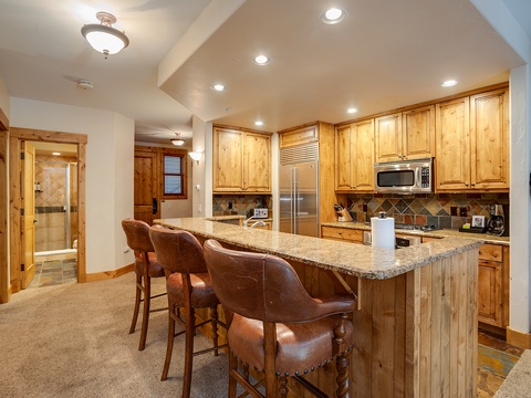 Gather around this spacious kitchen island with granite countertops, warm wood cabinetry, and modern stainless appliances—your perfect spot for morning coffee or evening conversations.