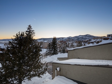 Winter sunrise illuminates the mountain resort town with snow-covered peaks and evergreen trees, marking a peaceful start to a ski getaway in this scenic alpine setting.