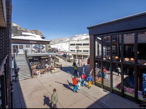 A vibrant ski village plaza surrounded by snow-dusted peaks, bustling shops, and mountain charm—your alpine adventure starts here.