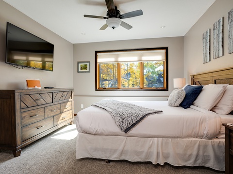 Sink into this plush bed with soft throws and pillows after a day exploring. Your private bedroom features a flat-screen TV, dresser, and large window with autumn forest views.