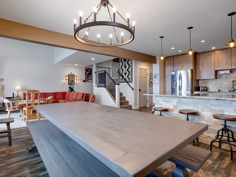 Step into your expansive open-concept retreat, where a dramatic circular chandelier illuminates rustic wood cabinetry, stone accents, and a generous island with bar seating—perfect for gathering with loved ones.