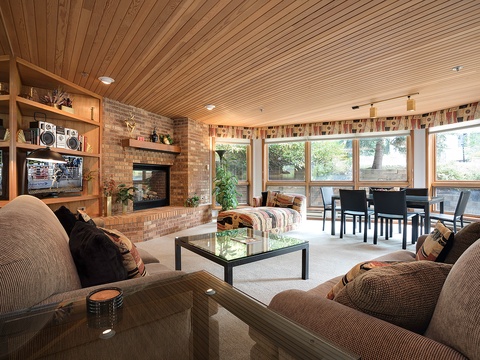Cozy living space with plush seating, a warm fireplace, and sunlit windows overlooking the peaceful outdoors—your perfect retreat for relaxing evenings and family gatherings.