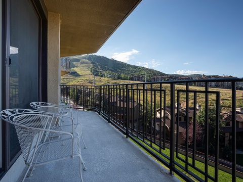 The property features a balcony overlooking scenic mountain slopes and nearby resort buildings, offering an elevated perspective of the surrounding area.