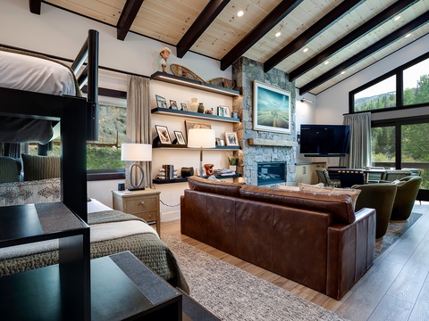 Sink into the leather sofa, warm up by the stone fireplace, and let the mountain views through floor-to-ceiling windows melt your stress away in this inviting living space.