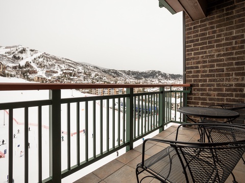 Balcony overlooking snow-covered slopes and alpine village, offering front-row access to winter mountain views and ski area activity.