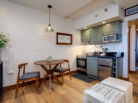 Your cozy dining nook flows seamlessly into a fully-equipped kitchenette, where warm wood floors and modern appliances create the perfect home base for cooking your favorite meals.