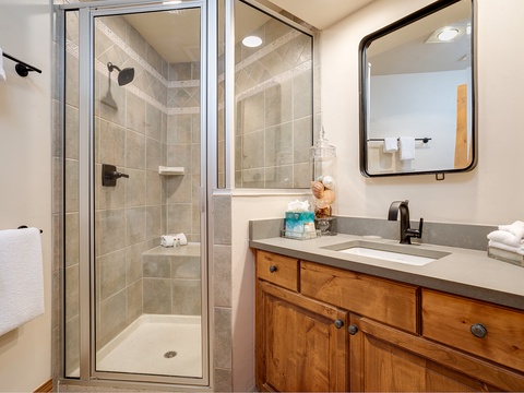 Step into your private bathroom featuring a beautifully tiled walk-in shower, warm wood vanity, and modern fixtures—perfectly designed for your comfort and relaxation.