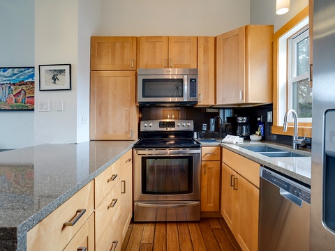 Your fully equipped kitchen features stainless steel appliances, ample counter space, and warm wood cabinetry—perfect for preparing home-cooked meals during your stay.