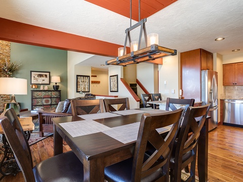 Gather around this spacious dining table with seating for eight, where warm wood tones and modern lighting create the perfect setting for your memorable vacation meals together.