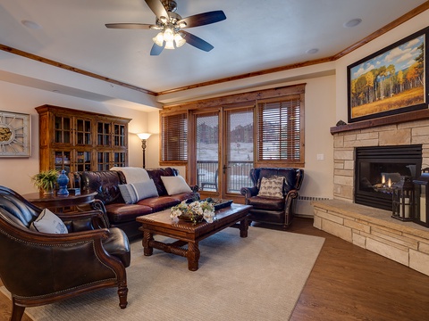 Unwind in your elegant living room with rich leather seating, a warming fireplace, and mountain views through classic wood-trimmed windows—your perfect retreat after a day of adventure.