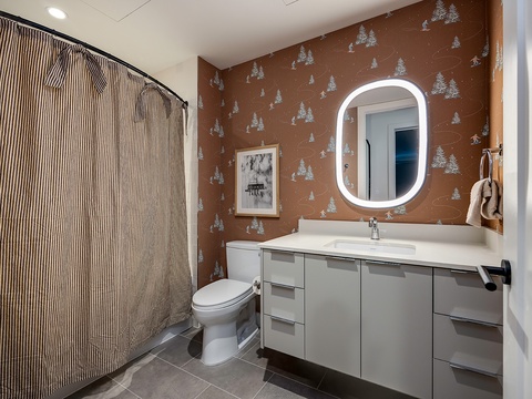 Step into your private retreat with a modern vanity, spa-like lighting, and charming woodland wallpaper that brings a touch of mountain magic to your daily routine.