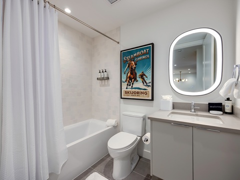 Your sleek bathroom features modern fixtures, ample counter space, and a backlit mirror that creates a bright, welcoming ambiance for your daily routine.