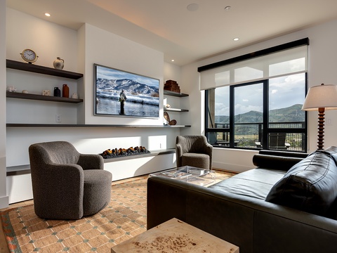 Settle into the plush seating and let your gaze wander to the sweeping mountain vistas framed by expansive windows. The modern fireplace adds warmth, while stylish shelving displays thoughtful touches that make this space feel like home.