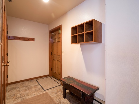 A welcoming entryway with rustic wood accents and open storage cubbies awaits your arrival. The coat hooks and bench provide a perfect spot to settle in after a day of adventure.