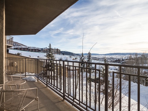 Expansive balcony offers sweeping views of snow-dusted mountain slopes and a tranquil valley, with outdoor seating perfect for crisp alpine mornings.