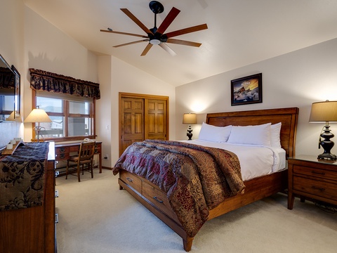 Your spacious bedroom welcomes you with rich wood furnishings, plush linens, and vaulted ceilings. A ceiling fan keeps you comfortable while bedside lamps and a desk offer convenience.