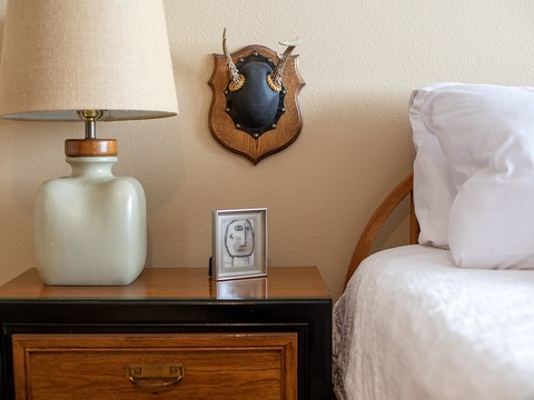 Unwind in your cozy bedroom with charming rustic touches, including a unique antler display and warm bedside lighting that create a welcoming mountain lodge atmosphere.
