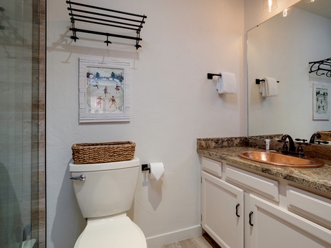 Your bathroom features a copper sink, granite countertops, and coastal artwork, blending beachy charm with modern comfort. Fresh towels and thoughtful storage make it feel like home.