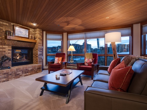 Unwind in your welcoming living space with a crackling fireplace, plush seating, and floor-to-ceiling windows framing stunning mountain vistas—perfect for cozy evenings after a day of adventure.