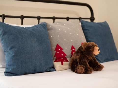 Cozy up in this charming bedroom where a friendly bear awaits to welcome your little ones. Blue accent pillows and festive touches create a warm, inviting space for your family's getaway.